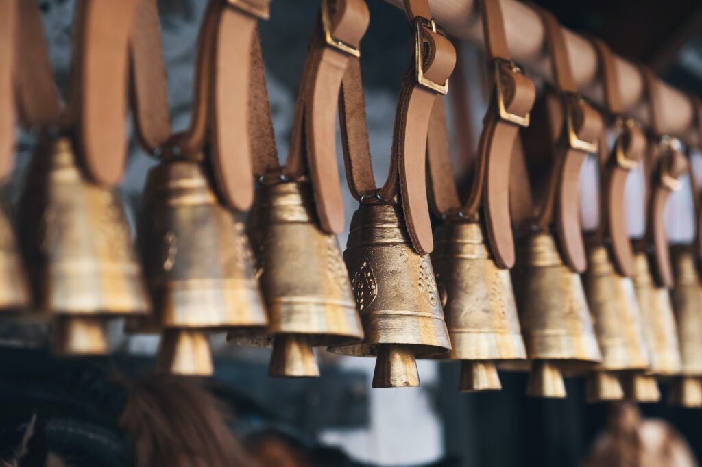 Brass bells hanging outside on leather straps