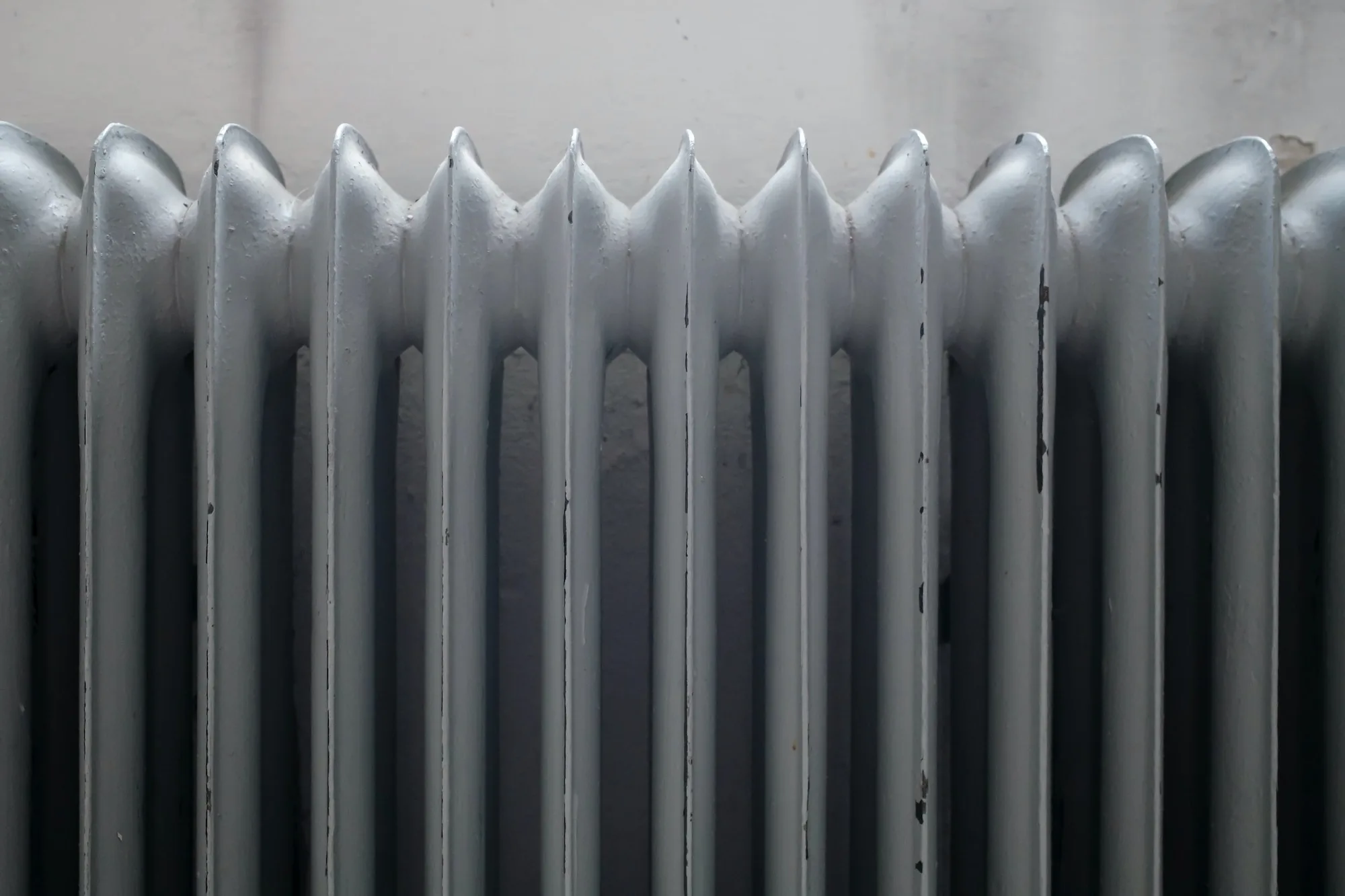 Old cast iron radiator with peeling paint before restoration