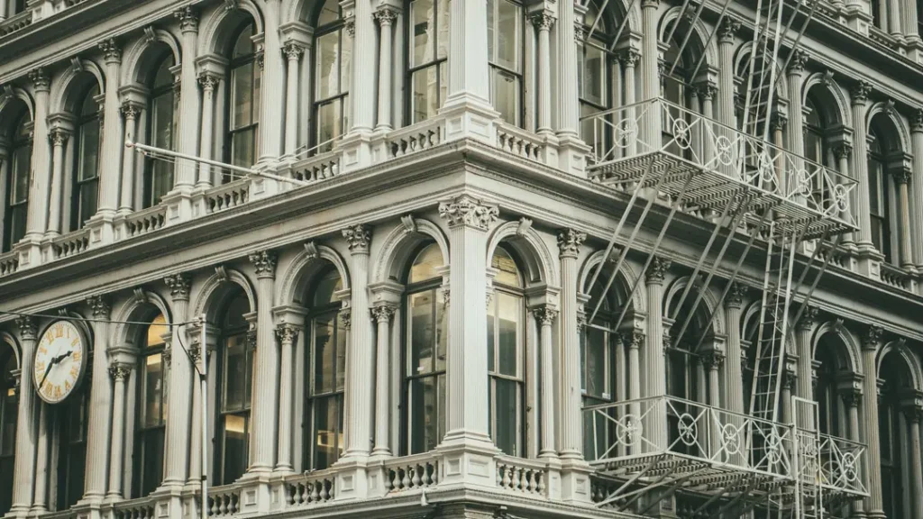 Historic cast iron building facade in Manhattan with ornate columns, arched windows, and steel fire escapes