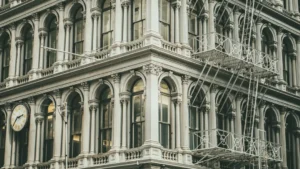 Historic cast iron building facade in Manhattan with ornate columns, arched windows, and steel fire escapes