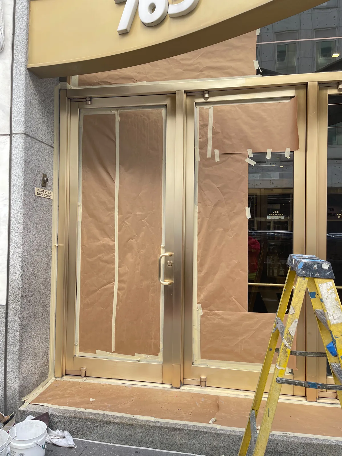 Brass entrance doors in Newark, New Jersey, bright again after refinishing, with the glass still masked