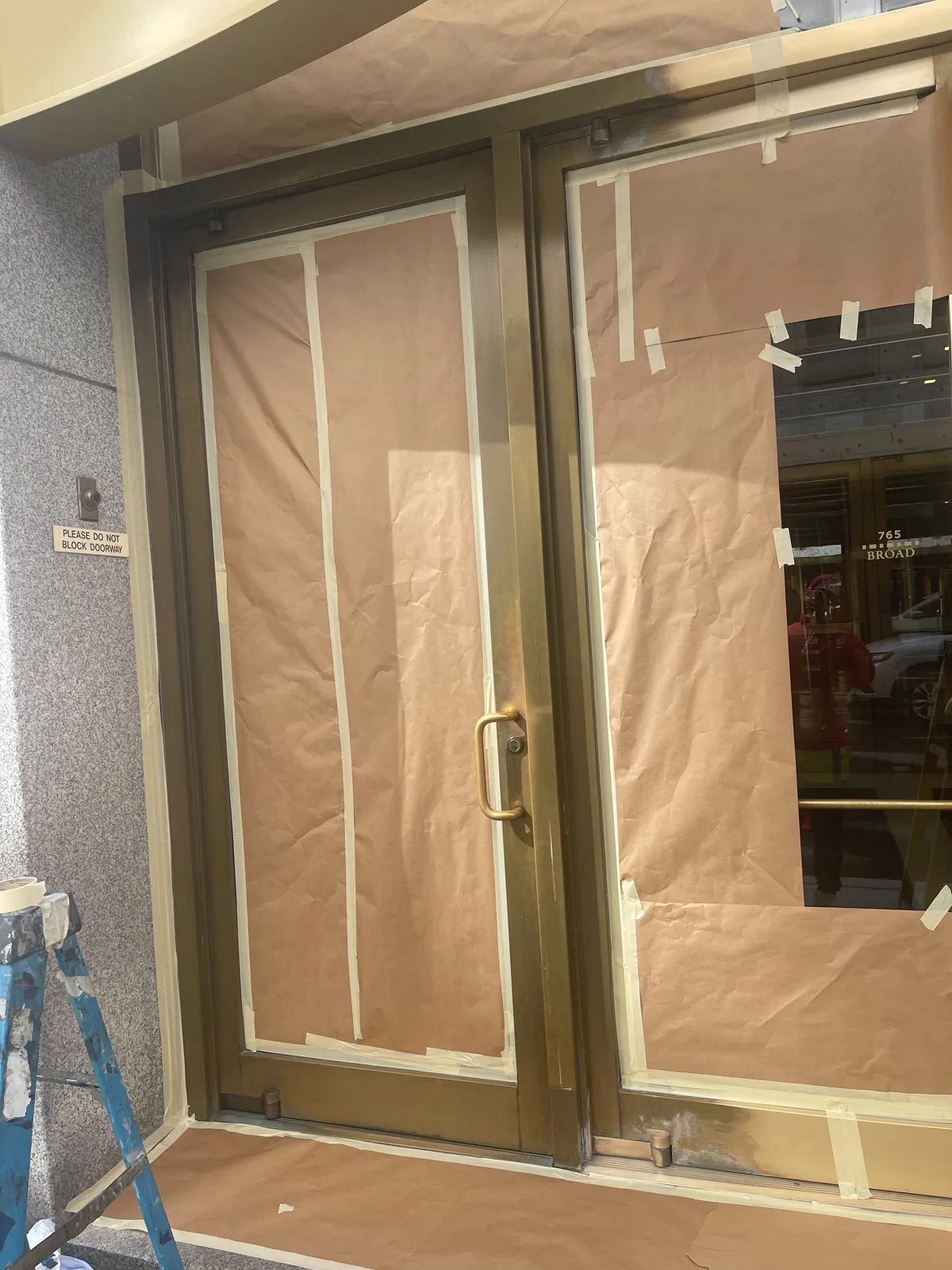 Brass entrance doors in Newark, New Jersey, darkened and masked off before refinishing